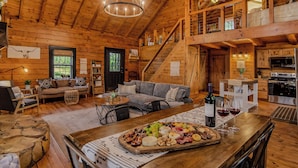 L’intérieur d’un chalet en bois comprend un coin repas, un canapé, un escalier et une cuisine.