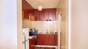 Una cocina compacta con armarios de madera, horno integrado y pileta.