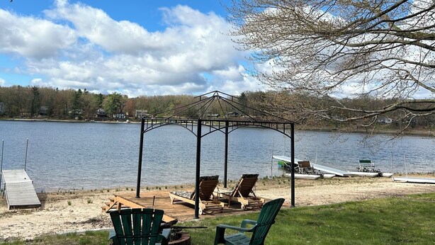 A lakeside deck with outdoor seating and a gazebo. - Cozy 2-bedroom cottage in charming Pierson, Michigan! (Pierson)