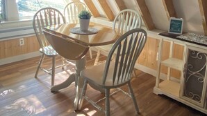 A dining area with a wooden table and chairs, a potted plant, and a sign reading 'Heaven closer beach.' - Cozy 2-bedroom cottage in charming Pierson, Michigan! (Pierson)