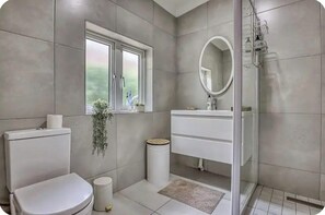 A bathroom with a toilet, sink, mirror, window, and shower. - French Bistro Studio - Home Near Sandton. High Wi-Fi Speed. Power&Water Backup (Sandton)
