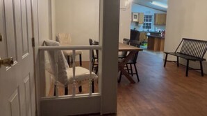 A hallway with a wooden floor, a white door, a bench, and a view into a dining area with a table and chairs. - Lakefront Home-Beautiful Views & Private Dock 15-20 to Clemson, Anderson,Seneca (Townville)