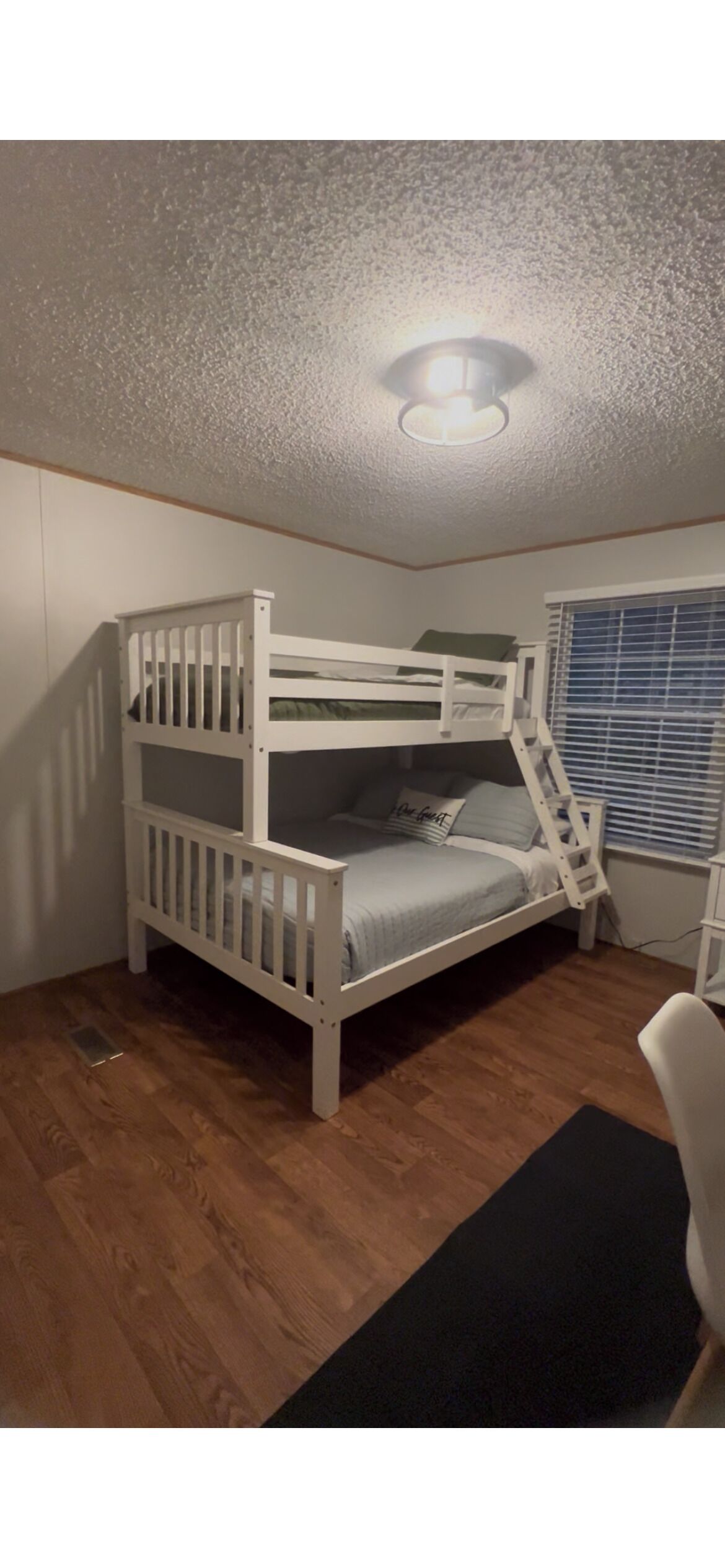 Una cama litera con escalera, un escritorio y una ventana con persianas.