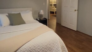 A bedroom with a bed, a nightstand, a lamp, a door, and a hallway leading to another room. - Lakefront Home-Beautiful Views & Private Dock 15-20 to Clemson, Anderson,Seneca (Townville)