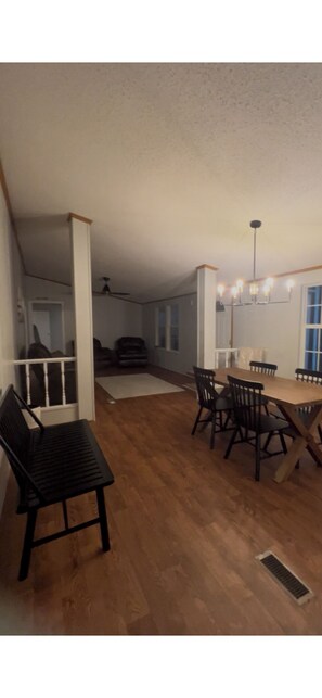 A dining area with a wooden table and chairs, a black bench, and a ceiling fan.
