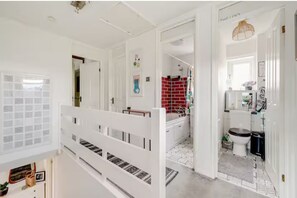 A multi-level interior with a staircase, a bathroom with red tiles, and a hallway leading to a door labeled 'THE INN'. - Serene garden 2-bed home with parking (London)