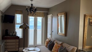 A bedroom with a bed, a sofa, a desk, a TV, and a window with a view. - Luxury Town House - Newquay 5 Mins to Beach (Newquay)