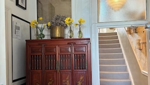 A staircase with a checkered floor, a wooden cabinet with floral decorations, and a wall with framed pictures. - Luxury Town House - Newquay 5 Mins to Beach (Newquay)