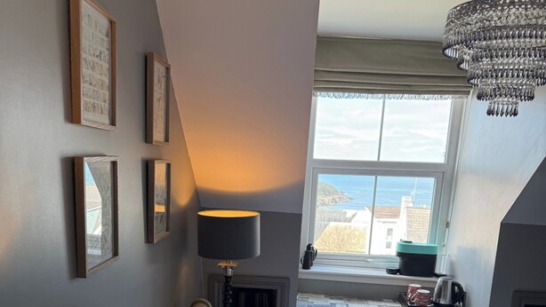 A bedroom with a bed, a bedside lamp, a window with a view, and a chandelier. - Luxury Town House - Newquay 5 Mins to Beach (Newquay)