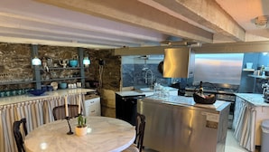 A kitchen with a marble island, a dining table with chairs, and a stone wall. - Luxury Town House - Newquay 5 Mins to Beach (Newquay)
