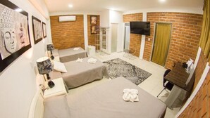 Une chambre d’hôtel avec deux lits, une télévision, un bureau et un mur en briques.