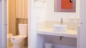 Une salle de bain d’hôtel avec des toilettes, un lavabo et une serviette sur le sol.