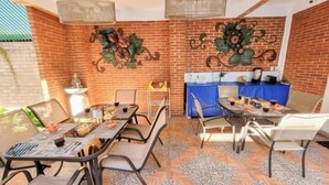 Un espace repas avec des murs en briques, des tables et des chaises à structure métallique, agrémenté d’œuvres d’art décoratives et d’une nappe bleue.