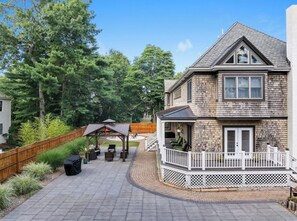 A two-story house with a covered patio area, a deck, and a fenced backyard.