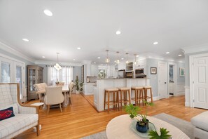 A spacious living area with a dining table, a sofa, and a kitchen with a central island.