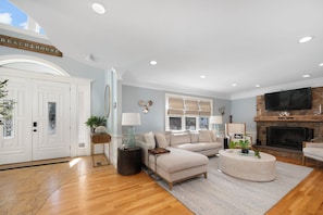 A living room with a sectional sofa, a round coffee table, a fireplace, and a TV.
