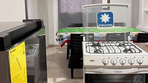 Une cuisine équipée d’une cuisinière à gaz, d’un réfrigérateur et d’une table recouverte d’une nappe.