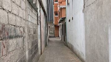 A narrow alleyway with brick paving, flanked by buildings with visible windows and doors.