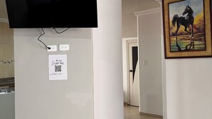 Une pièce dotée d’un téléviseur à écran plat fixé au mur, d’un tableau représentant un cheval et d’une porte donnant sur une autre pièce.