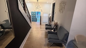 Un intérieur moderne avec un plancher en bois, un escalier et un coin salon avec des fauteuils.