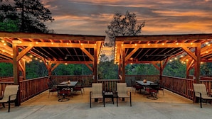 Une terrasse extérieure agrémentée de pergolas en bois, de guirlandes lumineuses et de mobilier d’extérieur.