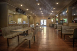 A restaurant interior with wooden tables and benches, a grill sign, and a view of the outdoors. - Flyin' Free Tepee | King Bed | Resort Access (Sevierville)