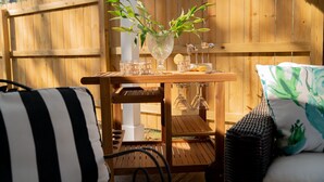 Un área de estar al aire libre con madera, que incluye una mesa, sillas y un sofá de mimbre.