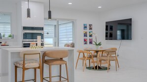 Une cuisine moderne dotée d’un îlot central, de tabourets de bar et d’un coin repas avec des chaises en bois.