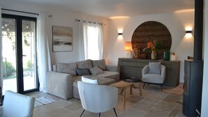 A modern living room with a sofa, armchairs, a coffee table, a fireplace, and a dining area. - Small house near Uzes and the Pont du Gard, ideal for 2 or 4 people (Saint-Maximin)