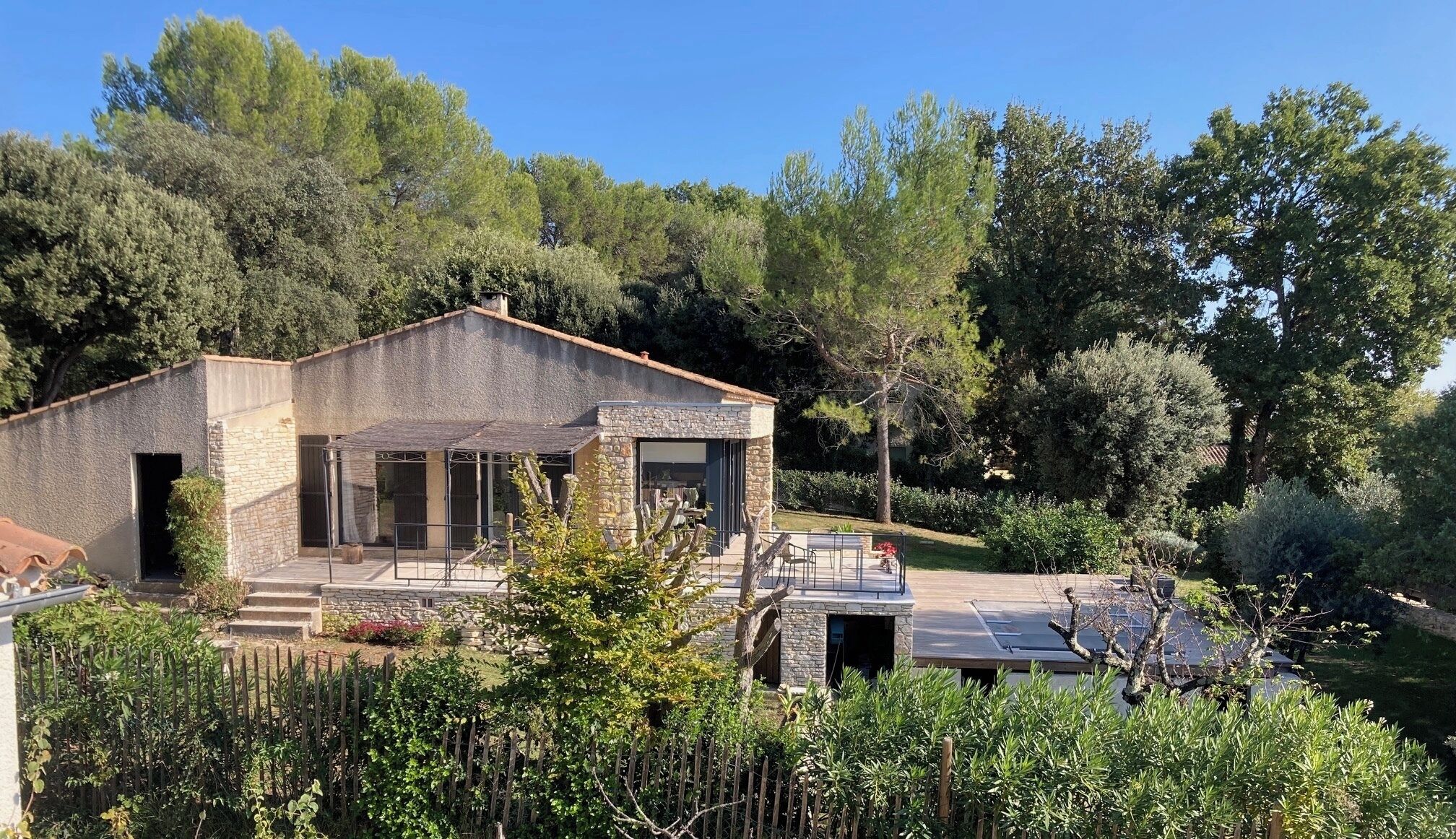 Une maison moderne avec une façade en pierre, de grandes fenêtres et un espace patio.