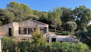 Una casa moderna amb façana de pedra, grans finestres i una zona de pati.