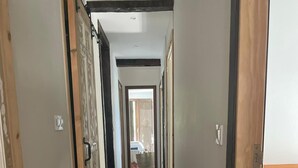 Un corridoio stretto con pavimento in legno e vista su una stanza con un letto.