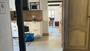 Cucina con mobili bianchi, forno a microonde e zona pranzo con sedia e tavolo.