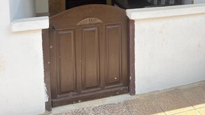 Un ingresso con una porta marrone, un muro in pietra, un lampadario e una panchina.