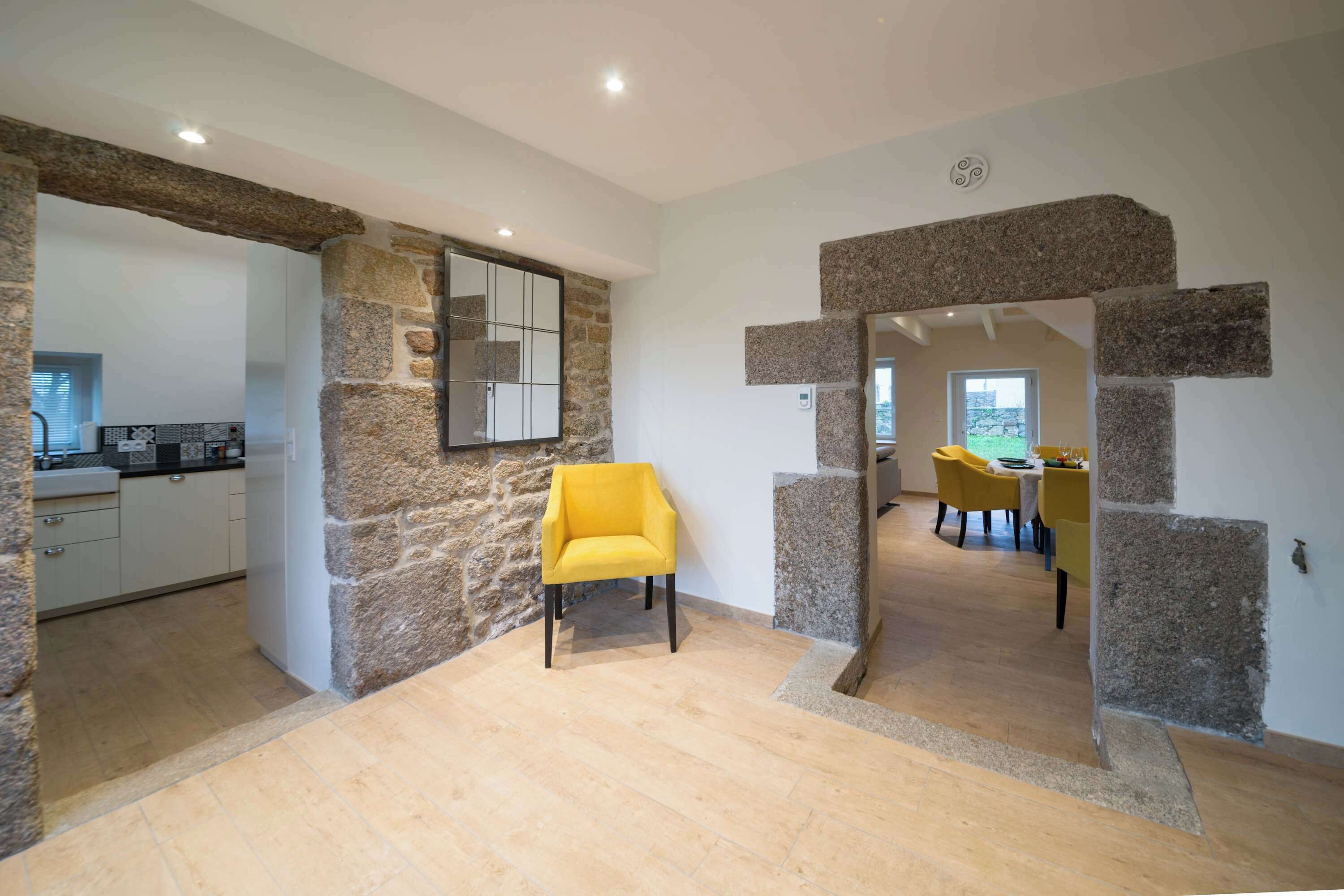 Een modern interieur met stenen muren, een gele stoel en een eethoek.