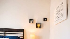 A bedroom with a bed, a nightstand with a lamp, and a framed quote on the wall. - Cozy Designer Suite | Gym & Pool | DART Access (Irving)