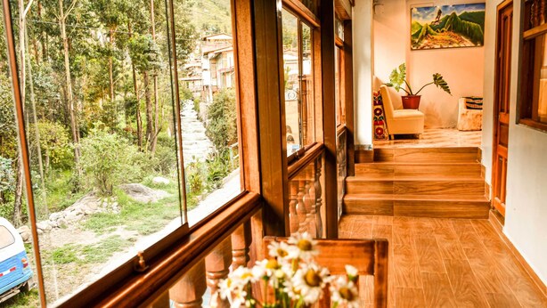 Eine Holztreppe führt zu einem Balkon mit Blick auf ein bewaldetes Gebiet und ein geparktes Auto.