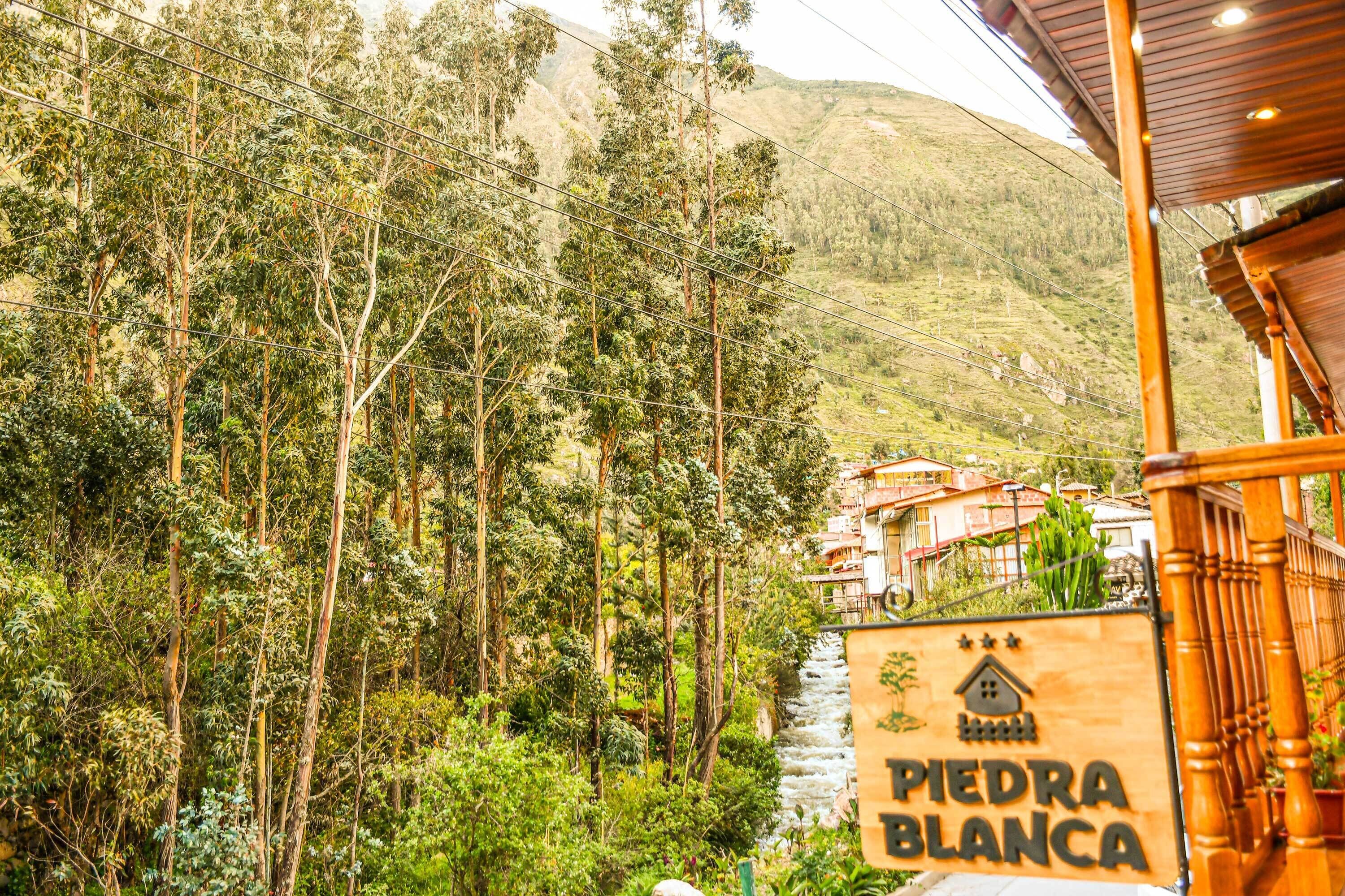 A sign for Piedra Blanca, surrounded by lush greenery and a river.