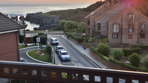 Ein Hotel an der Küste mit Blick auf das Meer, einer Kreisverkehr und parkenden Autos.
