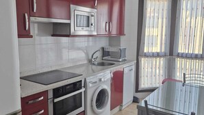 Eine kleine Küche mit Mikrowelle, Backofen, Waschmaschine und Spüle.