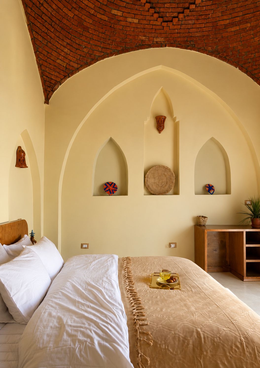 A bedroom with a brick ceiling, arched alcoves, and a bed with white linens.