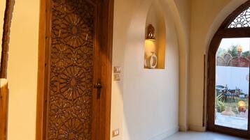 A room with a wooden door, a rug, and a small wall-mounted light fixture.