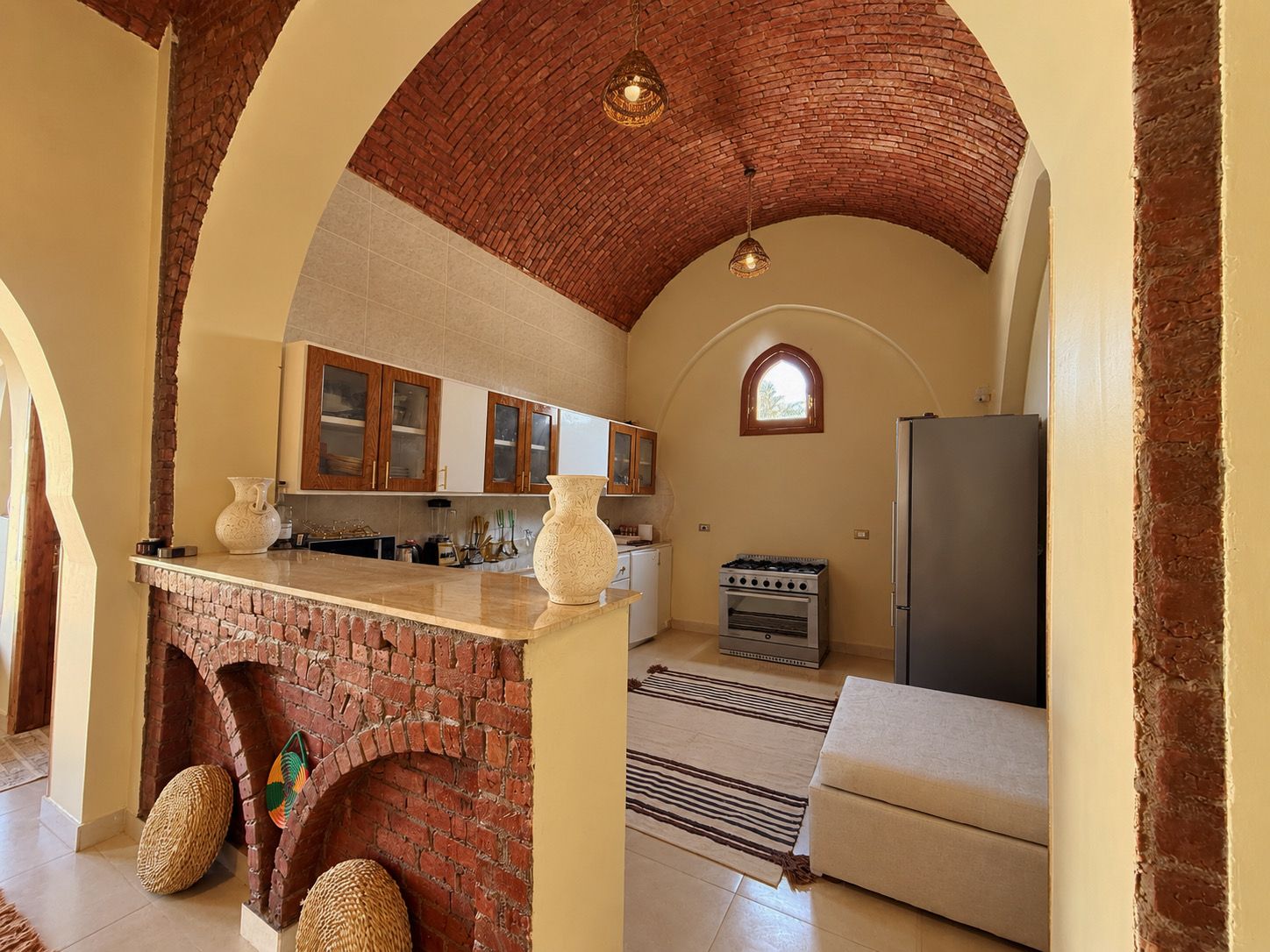 A kitchen with a brick fireplace, wooden cabinets, a stove, and a refrigerator.