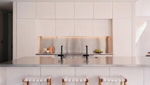 Eine moderne Küche mit einer zentralen Kochinsel, Barhocker und einer Spritzschutzwand.