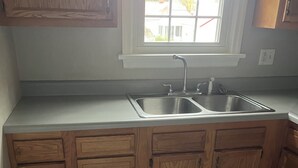 A kitchen with wooden cabinets, a double sink, and a window above the sink. - Cozy 2-bedroom house in fantastic Point Pleasant with AC (Point Pleasant)