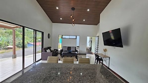 Un interior moderno con una isla de cocina, zona de estar y televisor montado en la pared.