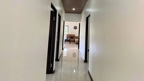 Un pasillo con techo de madera y paredes blancas que conduce a una sala de estar con un sofá y una mesa de centro.