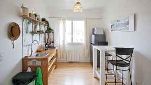 A kitchen with a wooden countertop, a sink, a hanging light fixture, and a dining area with chairs. - Le Shannon - Porte de Bordeaux (Pessac)