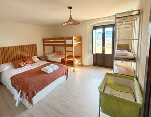 A bedroom with a bunk bed, a single bed, a hanging light fixture, a green storage unit, and a view through a door. - Farmhouse with swimming pool in the landscape of the Volcanic Zone of the Garrotxa. (Les Planes d'Hostoles)