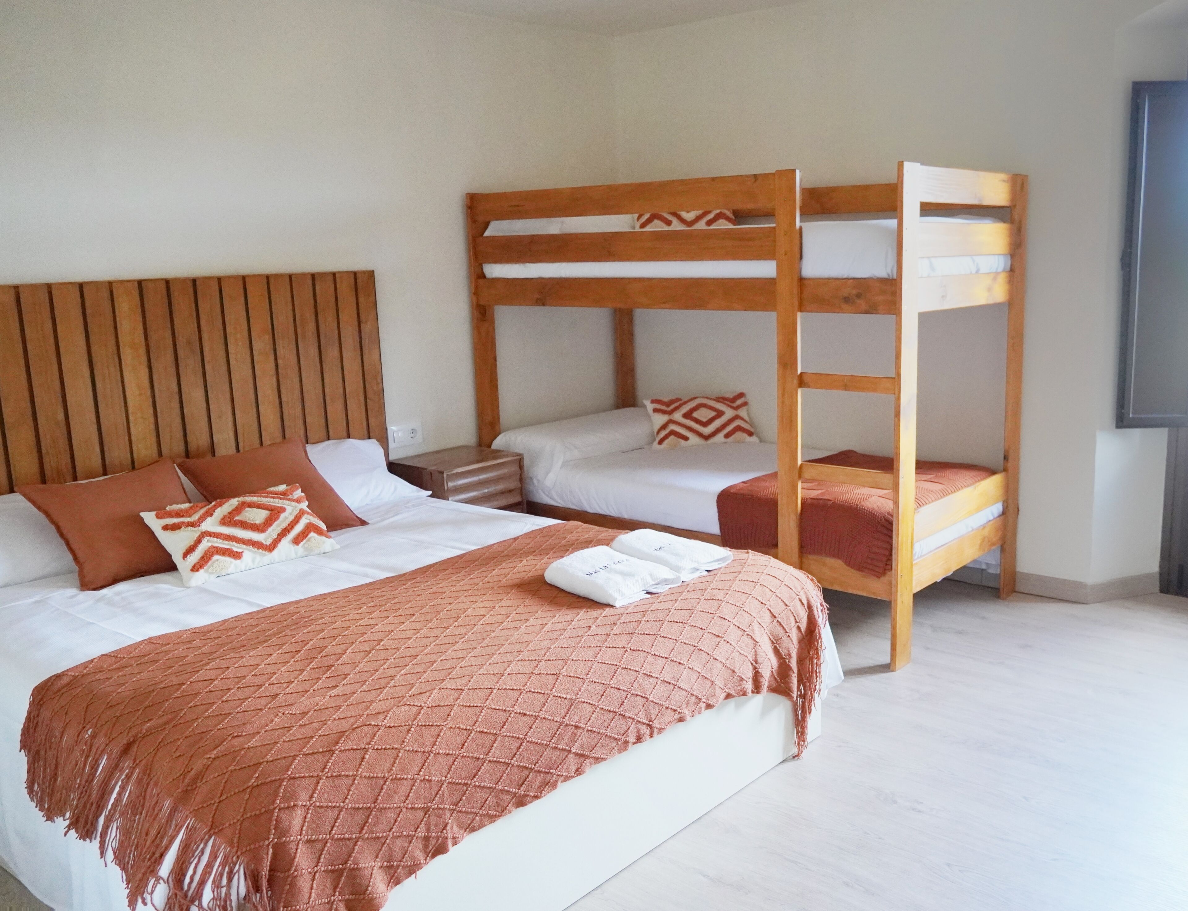 A room with a bunk bed, a single bed, and a nightstand.